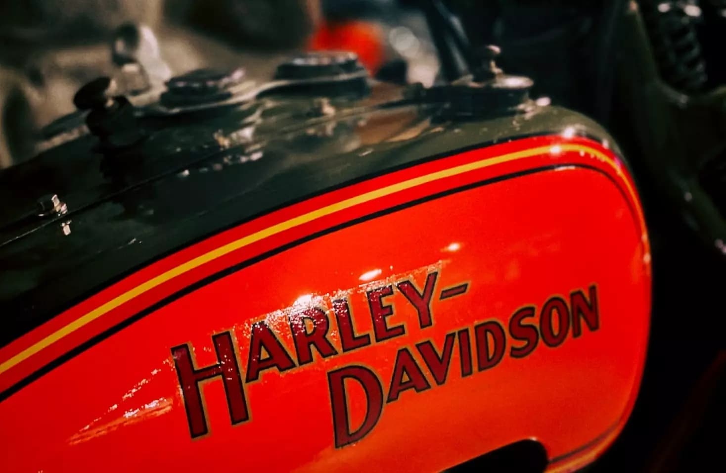 Close-up of a glossy orange Harley-Davidson fuel tank logo
