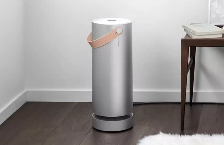Silver Molekule air purifier with a leather handle in a living room corner